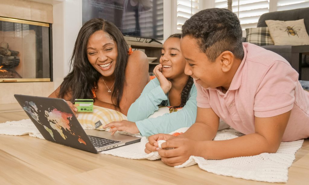 A happy family of three enjoying online shopping together on a laptop in a cozy living room.